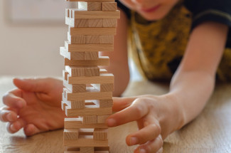Kind baut mit Jenga Steinen einen Turm